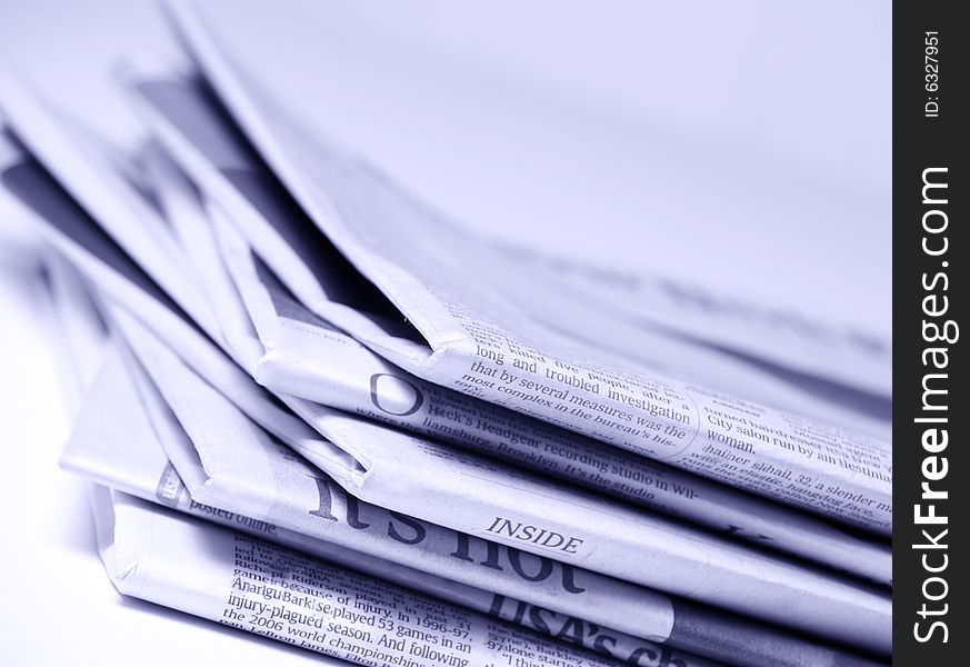 Blue tinted newspapers on light background shot with very shallow depth of focus. Blue tinted newspapers on light background shot with very shallow depth of focus