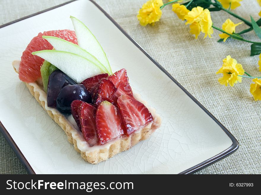 Close up of a fruit cake with strawberry, green apple, grapes, kiwi and grapefruit. Focus on the middle part.