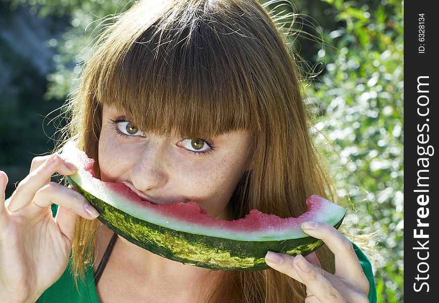 Pretty girl in green dress eating watermelon. Pretty girl in green dress eating watermelon