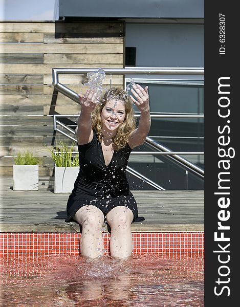 Young blonde woman splashing water at the pool