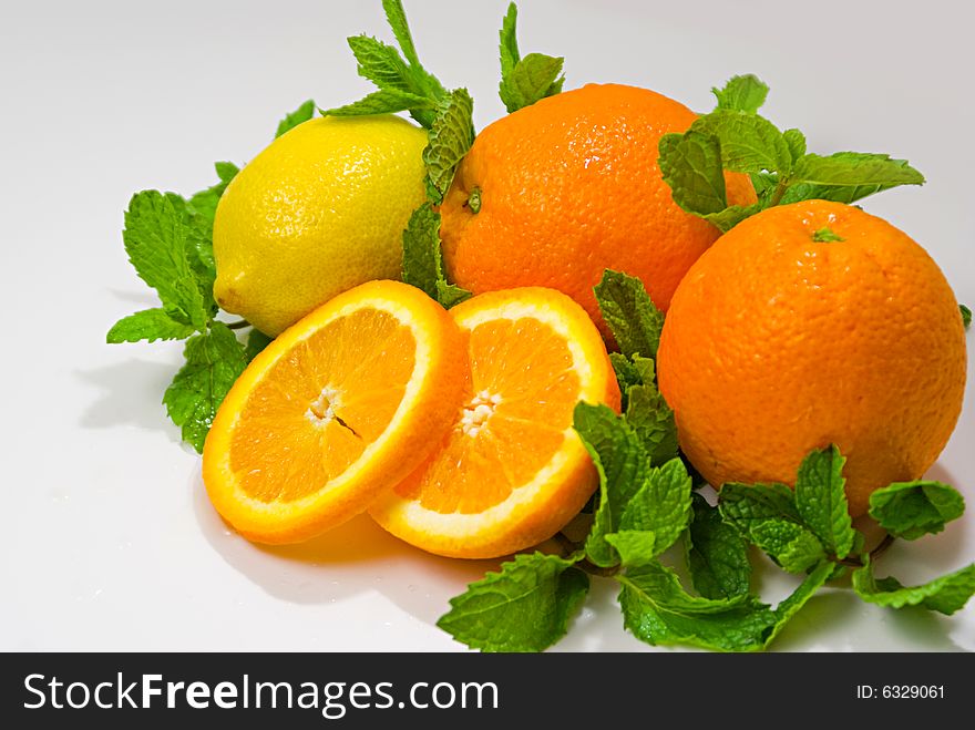 A group of oranges and lemon arranged with mint leaves. A group of oranges and lemon arranged with mint leaves