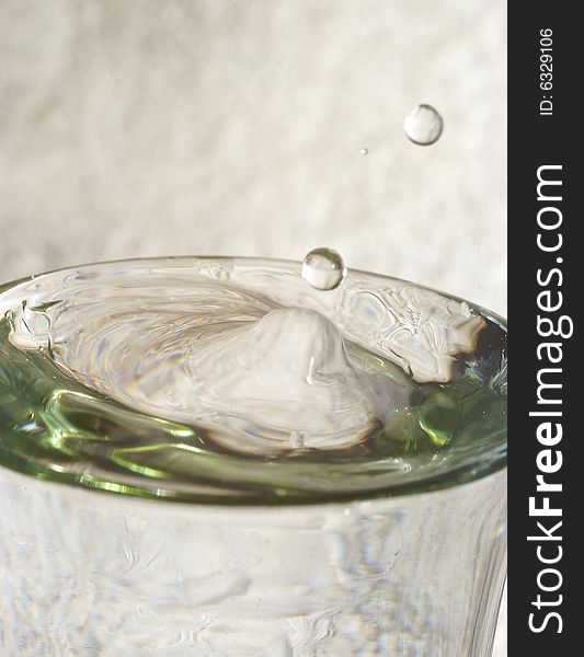 Droplets of water splashing from glass of water with reflections and highlights. Droplets of water splashing from glass of water with reflections and highlights