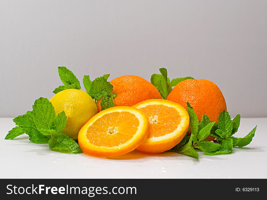 A group of oranges and lemon arranged with mint leaves. A group of oranges and lemon arranged with mint leaves