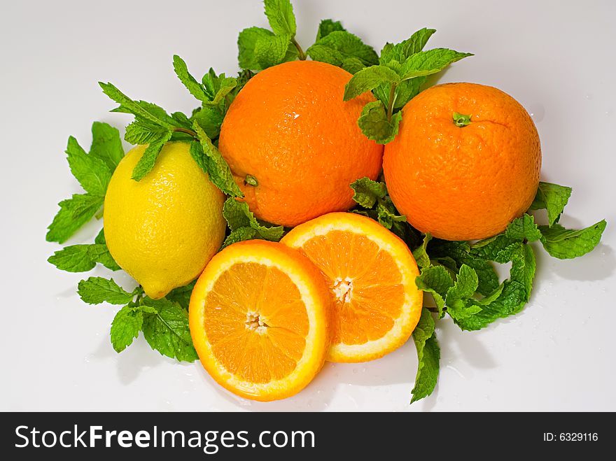 A group of oranges and lemon arranged with mint leaves. A group of oranges and lemon arranged with mint leaves