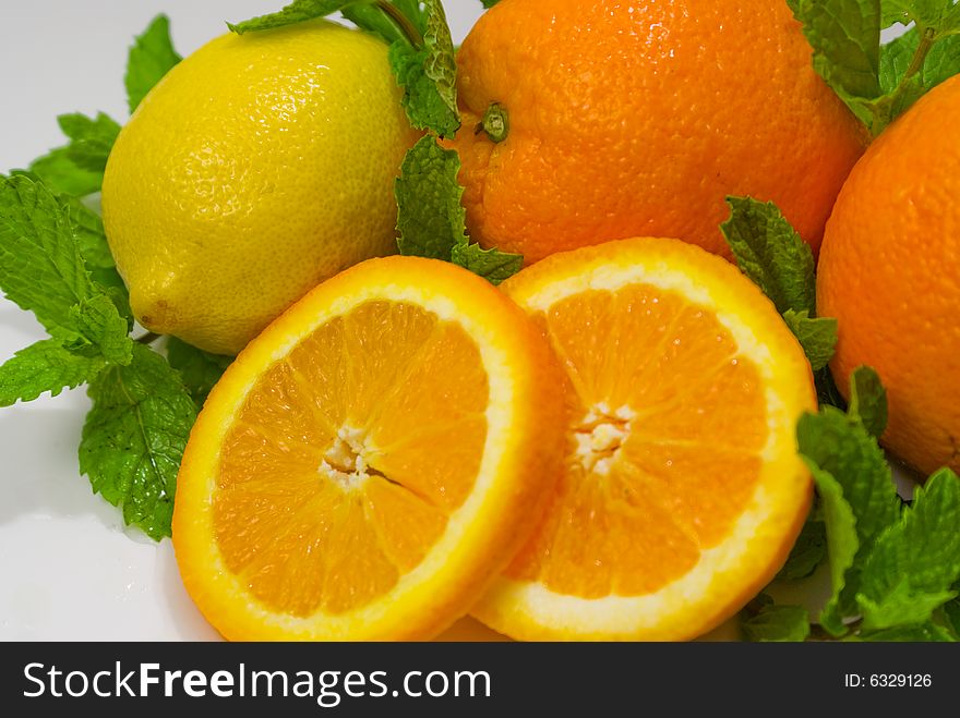 A group of oranges and lemon arranged with mint leaves. A group of oranges and lemon arranged with mint leaves