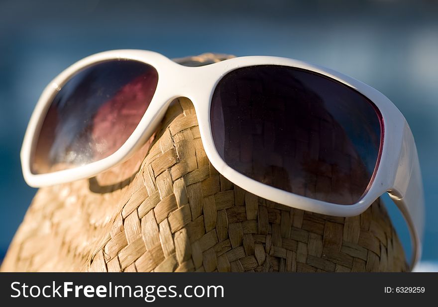 A Straw Hat With Sun Glasses Sitting Beside Pool