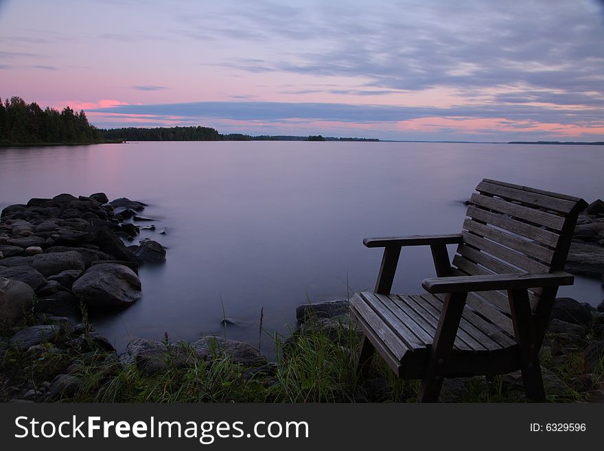 Sunset by the lake with empty chair, long exposure