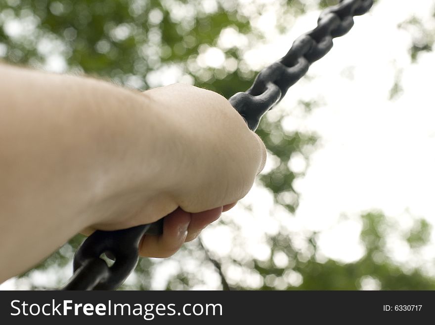 Photo of a hand gripping a chain from a tire swing. Photo of a hand gripping a chain from a tire swing