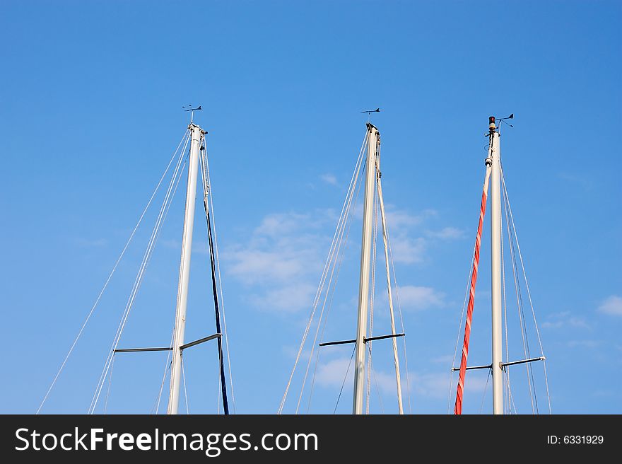 The upper parts of the masts of three sailing boats. The upper parts of the masts of three sailing boats