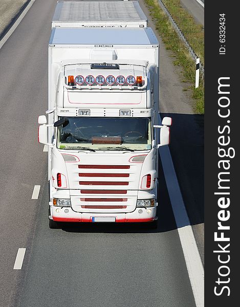 Large white truck, shot from above, driving head-on. trademarks removed, any text or stripes are standards. Large white truck, shot from above, driving head-on. trademarks removed, any text or stripes are standards.