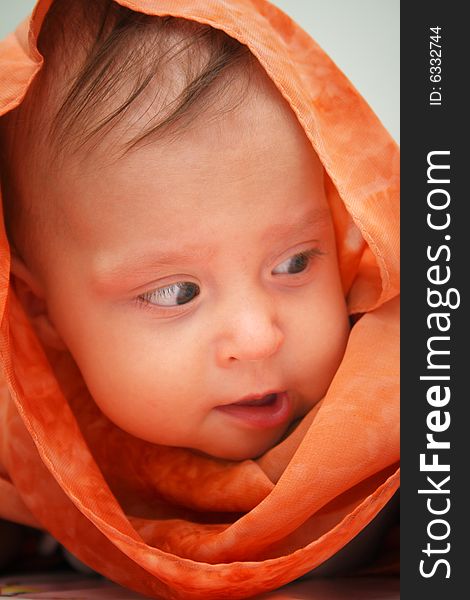 Little baby wrapped in orange shawl