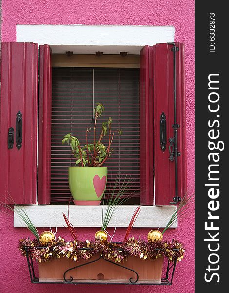 A flower pot with pink heart in window on pink wall. A flower pot with pink heart in window on pink wall