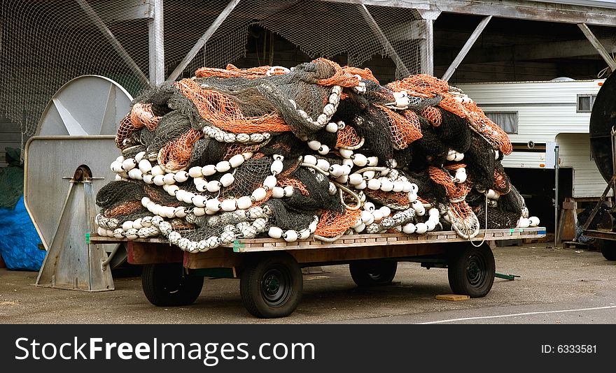 A pile of commercial fishing nets on a trailer at a harbor. A pile of commercial fishing nets on a trailer at a harbor