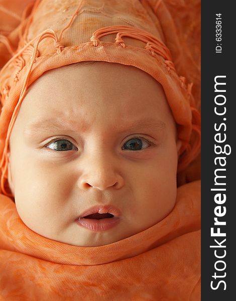 Little baby wrapped in orange shawl