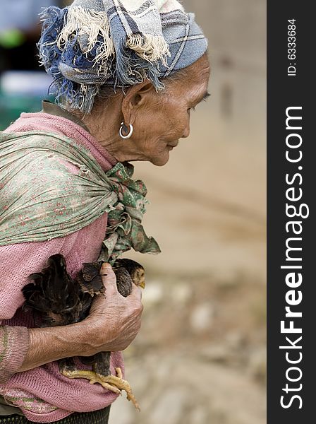 Asia, old woman with chicken in a village in Laos