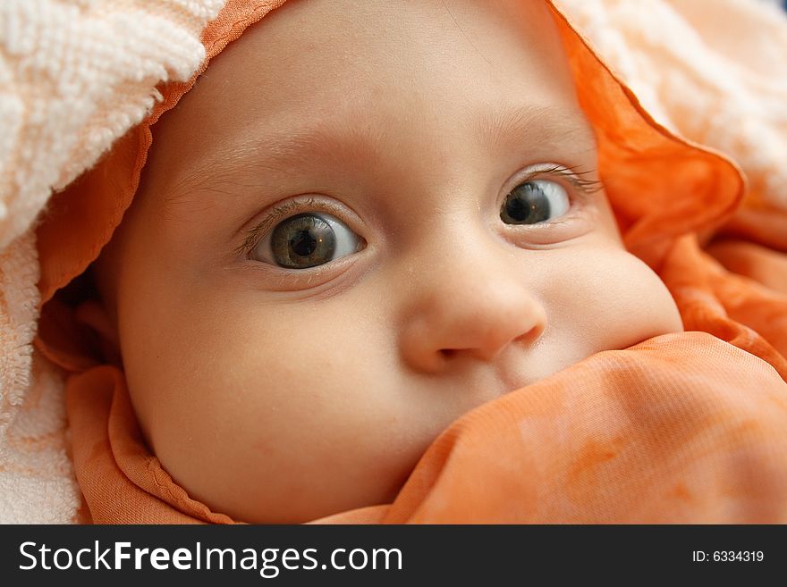 Little baby wrapped in orange shawl