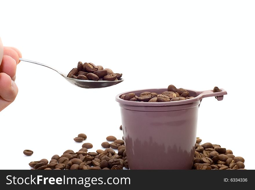 Hand with spoon. Cup with coffee beans on white