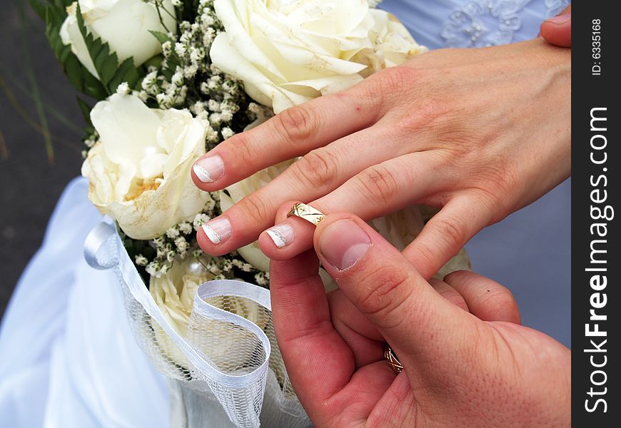 Groom putting ring on bride's finger. Groom putting ring on bride's finger