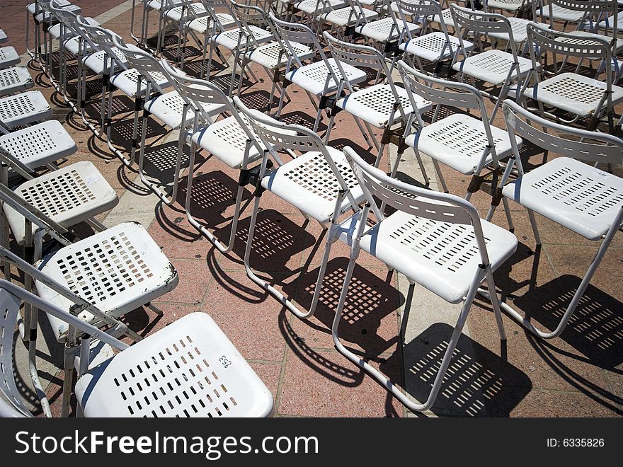 White Chairs Outdoors in the Sun and In a Row.