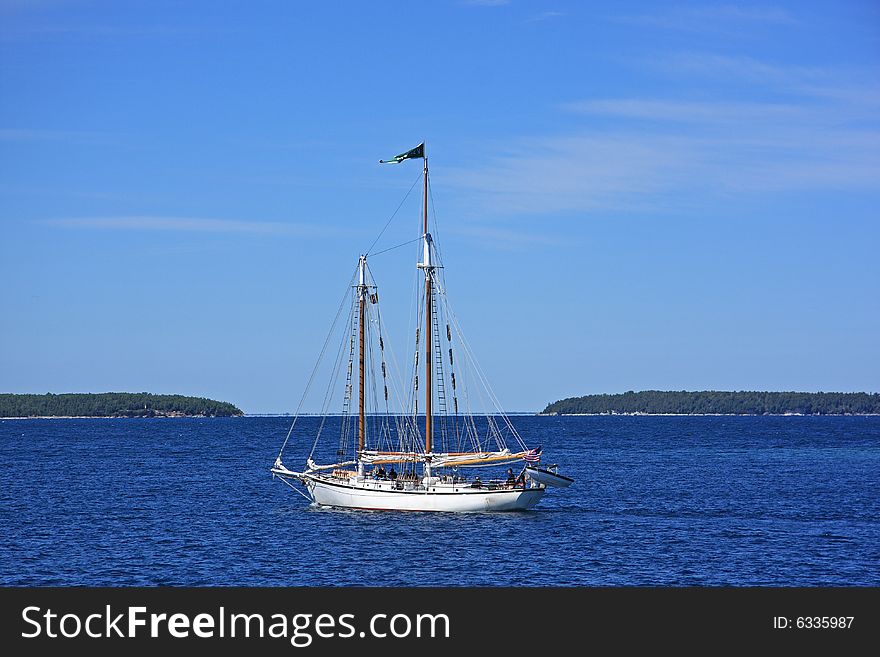 Wooden sailboat on sunny lake leaving harbour