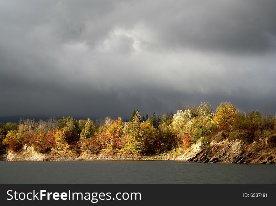 Autumn tree and bushes on background of storm cloud, low blood pressure. Autumn tree and bushes on background of storm cloud, low blood pressure