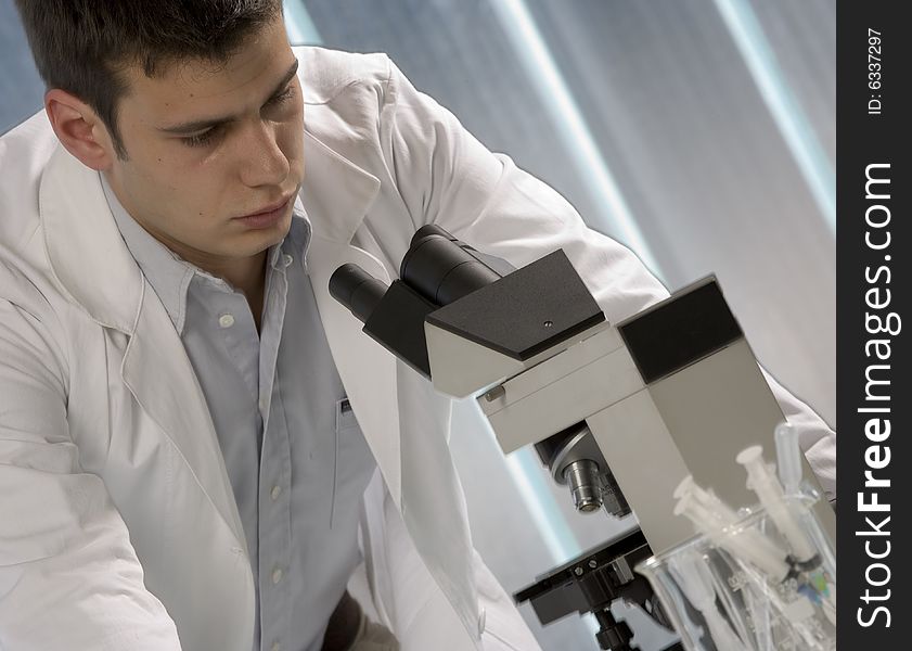 Male researcher looking through a microscope in a