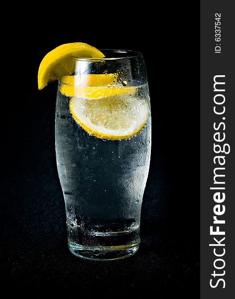 A refreshing glass of water, decorated with lemon.