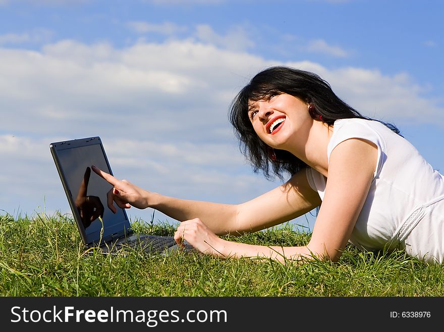 Funny woman with laptop on the green grass