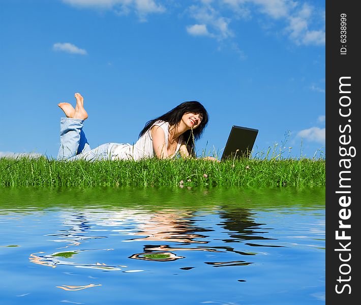 Pretty woman with laptop on the green grass