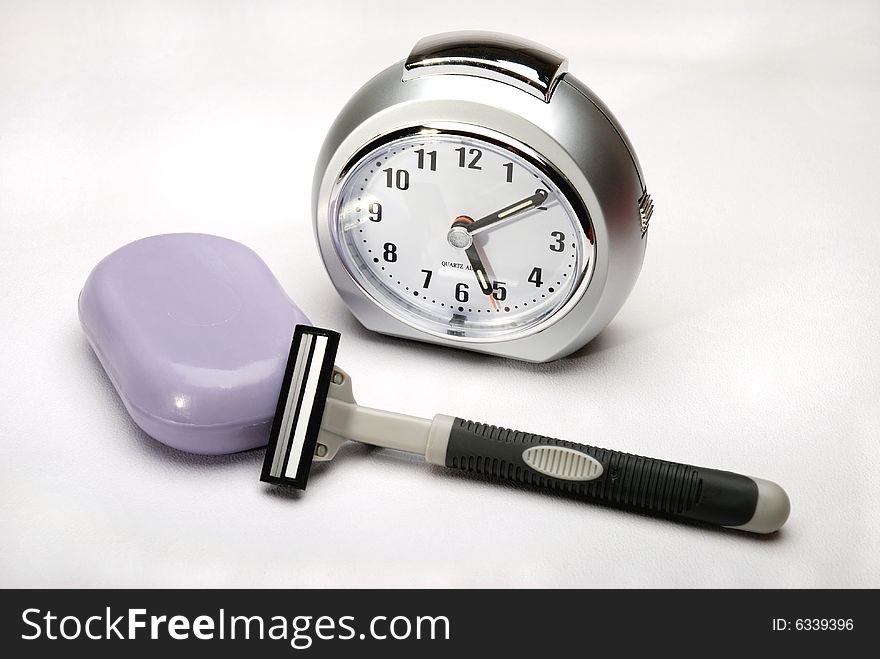 Alarm clock on a white linen background with a safety razor and lavender soap. Alarm clock on a white linen background with a safety razor and lavender soap