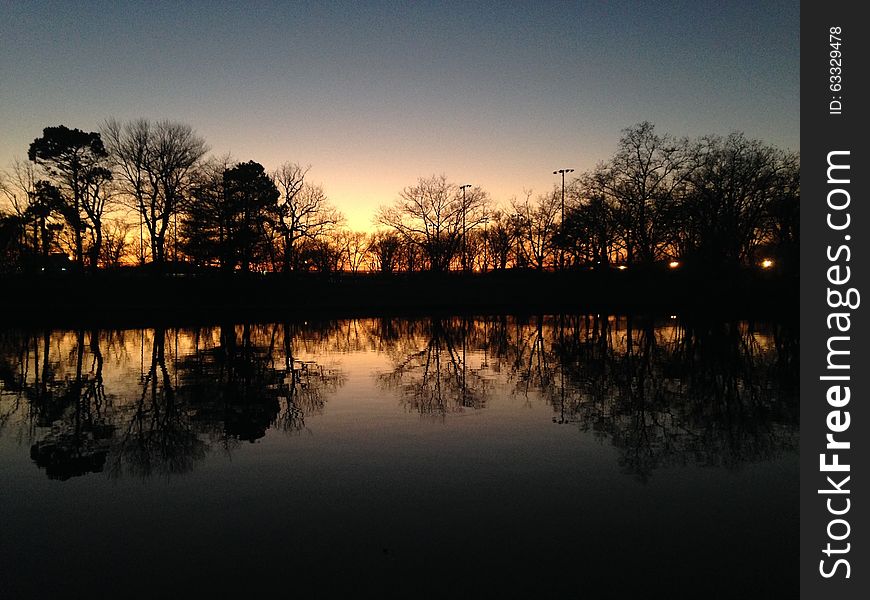 Trees Reflecting in a Pond Surface during Sunset in Winter in Lincoln Park in Jersey City, NJ. Trees Reflecting in a Pond Surface during Sunset in Winter in Lincoln Park in Jersey City, NJ.