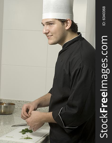 Young chef holding parsleyon a cutting board on a counter top. Vertically framed photo. Young chef holding parsleyon a cutting board on a counter top. Vertically framed photo.