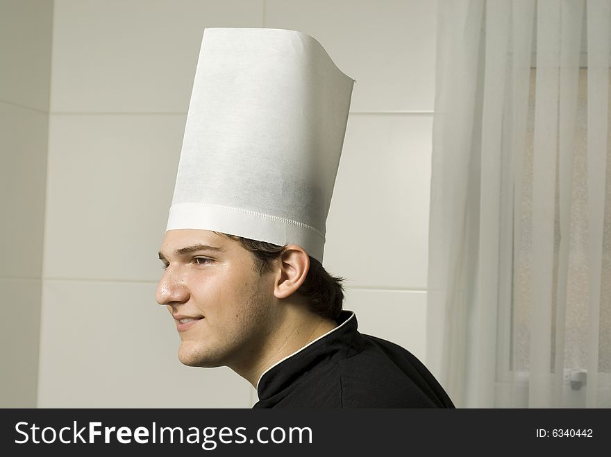 Smiling young chef in a chef's hat . Horizontally framed photo.