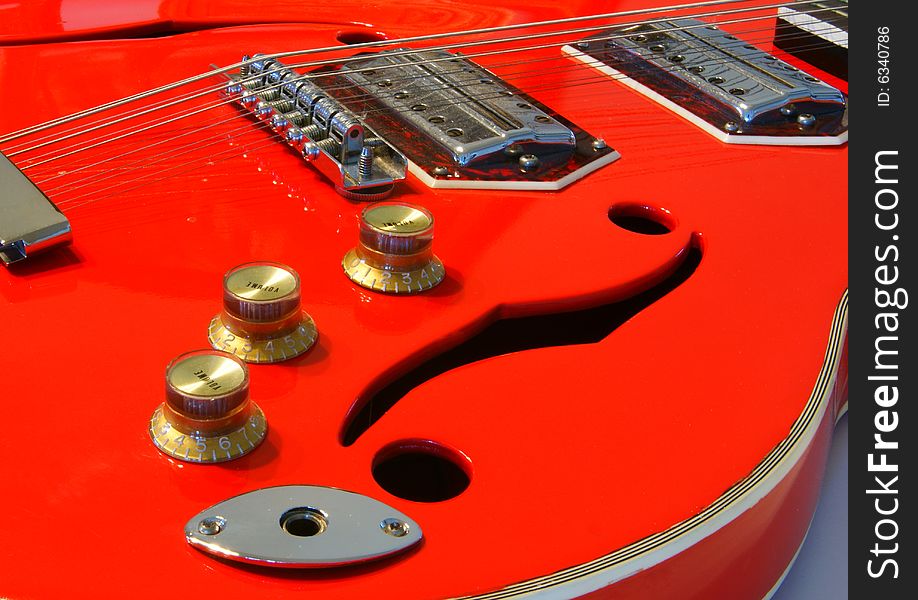 A red electric acoustic guitar closeup with sound holes. A red electric acoustic guitar closeup with sound holes