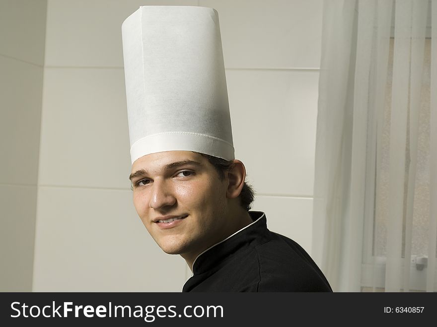 Smiling young chef in a chef's hat . Horizontally framed photo.