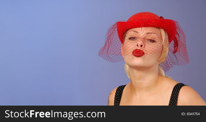 Gorgeous fifties style pinup blond girl in red hat blowing a kiss with space for text. Gorgeous fifties style pinup blond girl in red hat blowing a kiss with space for text