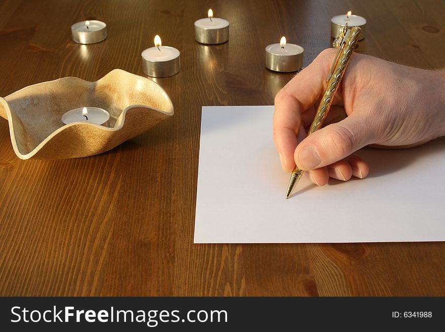 Hand wiriting with golden pen with candles. Hand wiriting with golden pen with candles