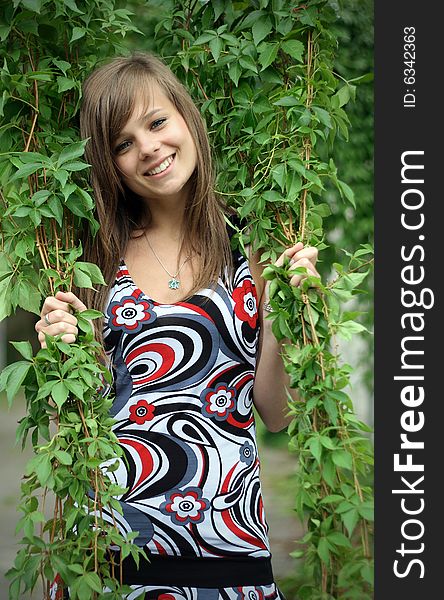 A picture of a girl, smiling to the camera being within the branches. A picture of a girl, smiling to the camera being within the branches