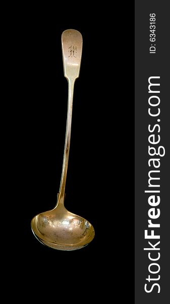 A tarnished antique silver serving ladle isolated on a black background