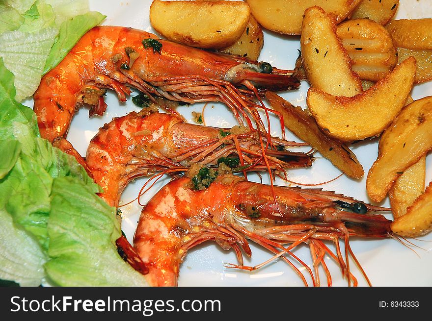 Group of jumbo shrimps garnished with potatoes and lettuce on a plate