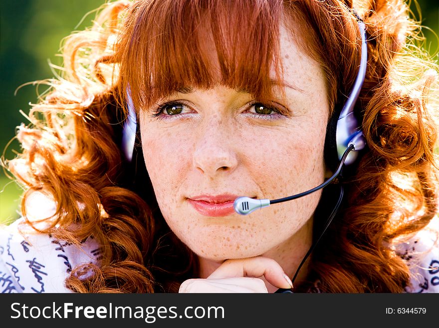 Close-up portrait of red-haired lovely young woman with headset outdoors. Close-up portrait of red-haired lovely young woman with headset outdoors