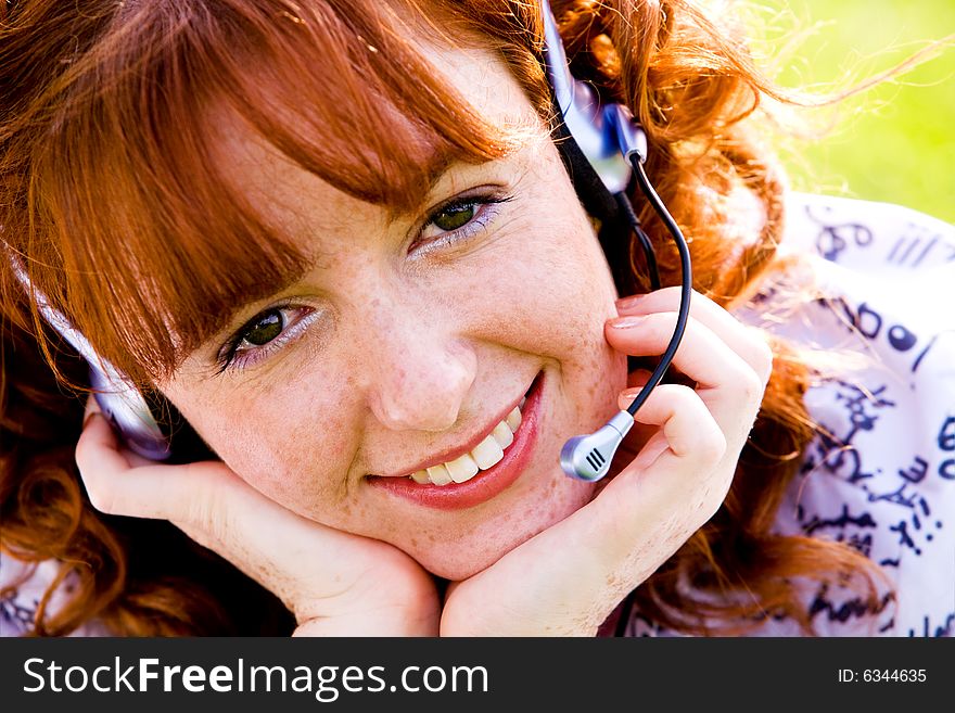 Close-up portrait of red-haired lovely young woman with headset outdoors. Close-up portrait of red-haired lovely young woman with headset outdoors