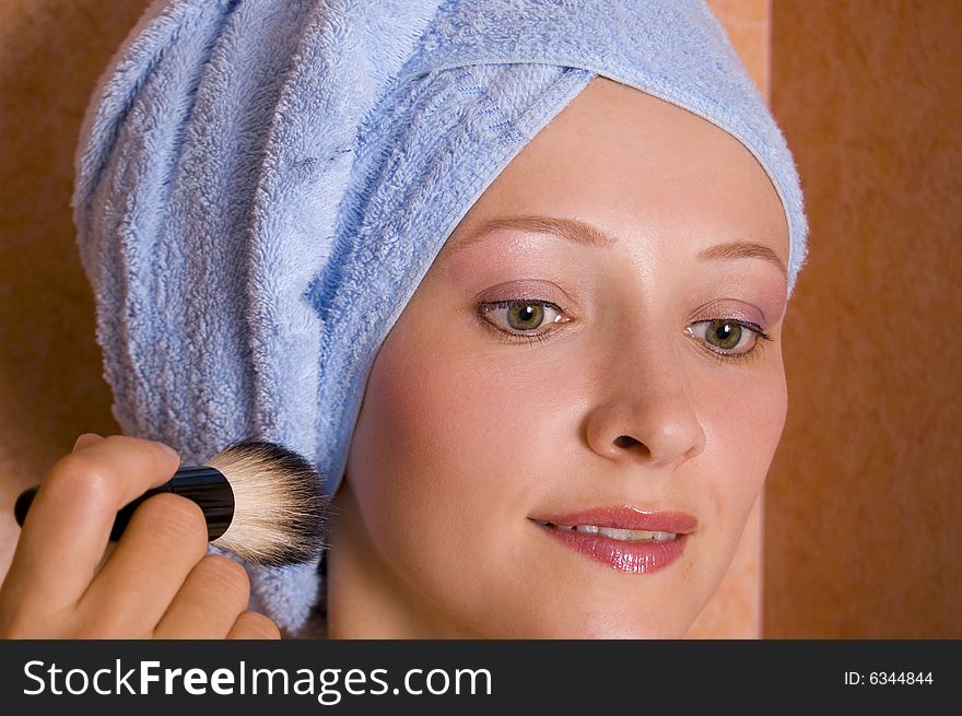 Beautiful young woman doing make-up in the bathroom.