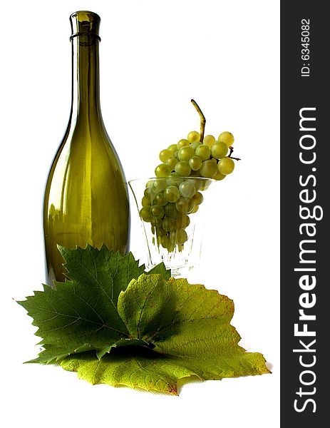 Grapes - fruits and leaves on a white backgroung with an empty glass and green bottle. Grapes - fruits and leaves on a white backgroung with an empty glass and green bottle.