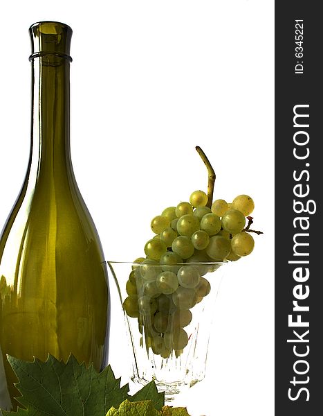 Grapes - fruits and leaves on a white backgroung with an empty glass and green bottle. Grapes - fruits and leaves on a white backgroung with an empty glass and green bottle.