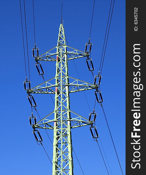 High-voltage pylon against a blue sky. Detail the upper structure. High-voltage pylon against a blue sky. Detail the upper structure.