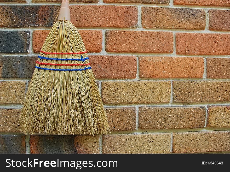 A broom hanging on red brick wall. A broom hanging on red brick wall