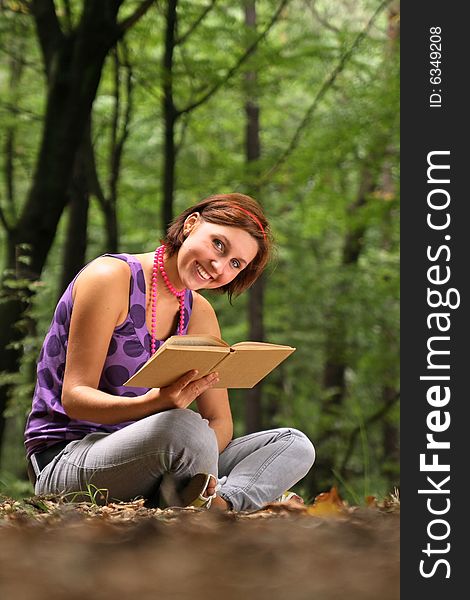 Photo of a teenager reading a book in a forest. Photo of a teenager reading a book in a forest