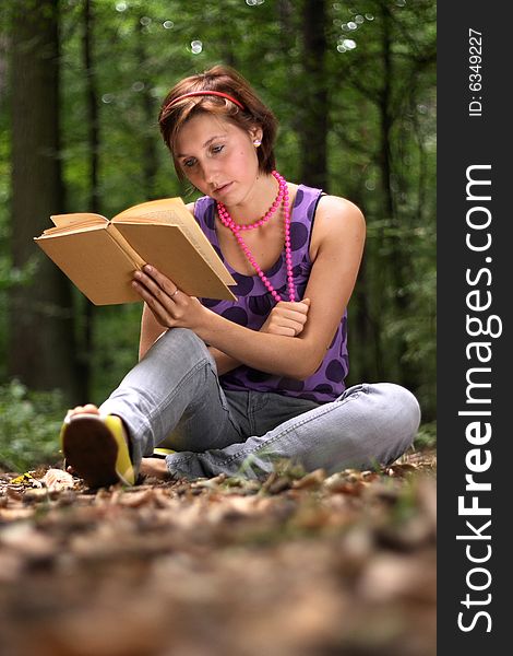 Photo of a teenager reading a book in a forest. Photo of a teenager reading a book in a forest