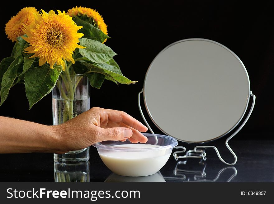 Objects on the toilet table and the hand of woman which uses the cream